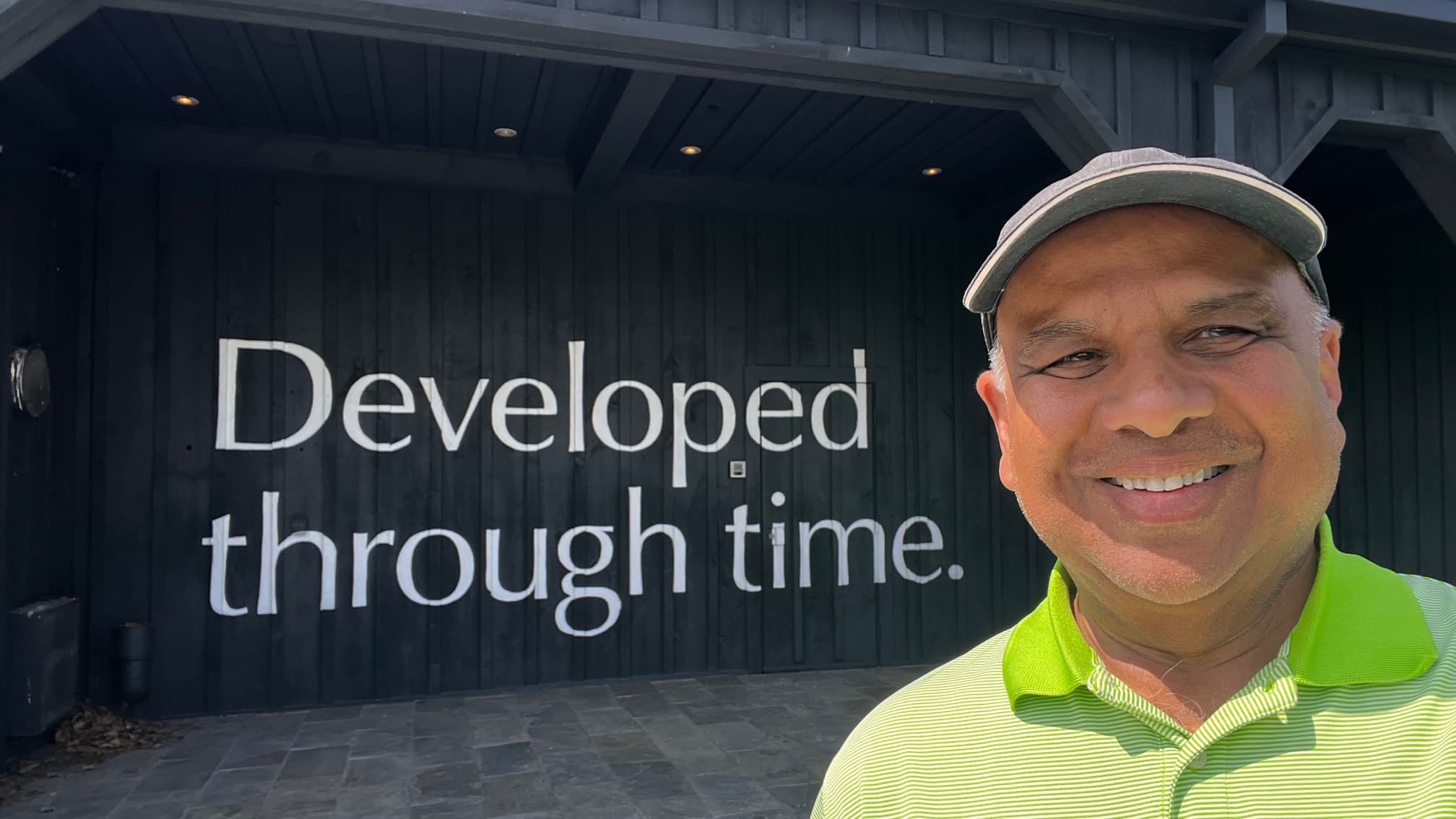 Randy Gananathan, candidate for Mayor of Pelham, in front of a wall reading 'Developed through time.'